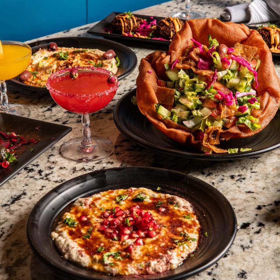 Middle-eastern dishes: fattoush salad in a bread bowl, baba ghanoush, falafel, and two cocktails.