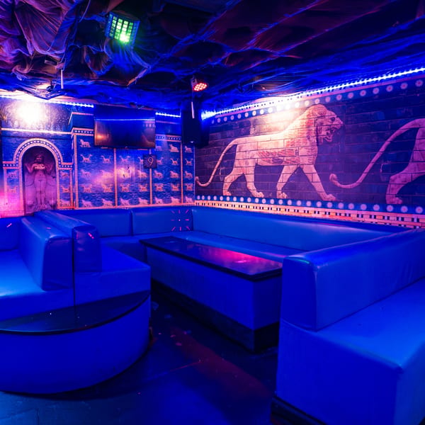 Babylon Cafe's interior with blue booths, tables, and walls featuring ancient Middle Eastern-style lion and figure murals.
