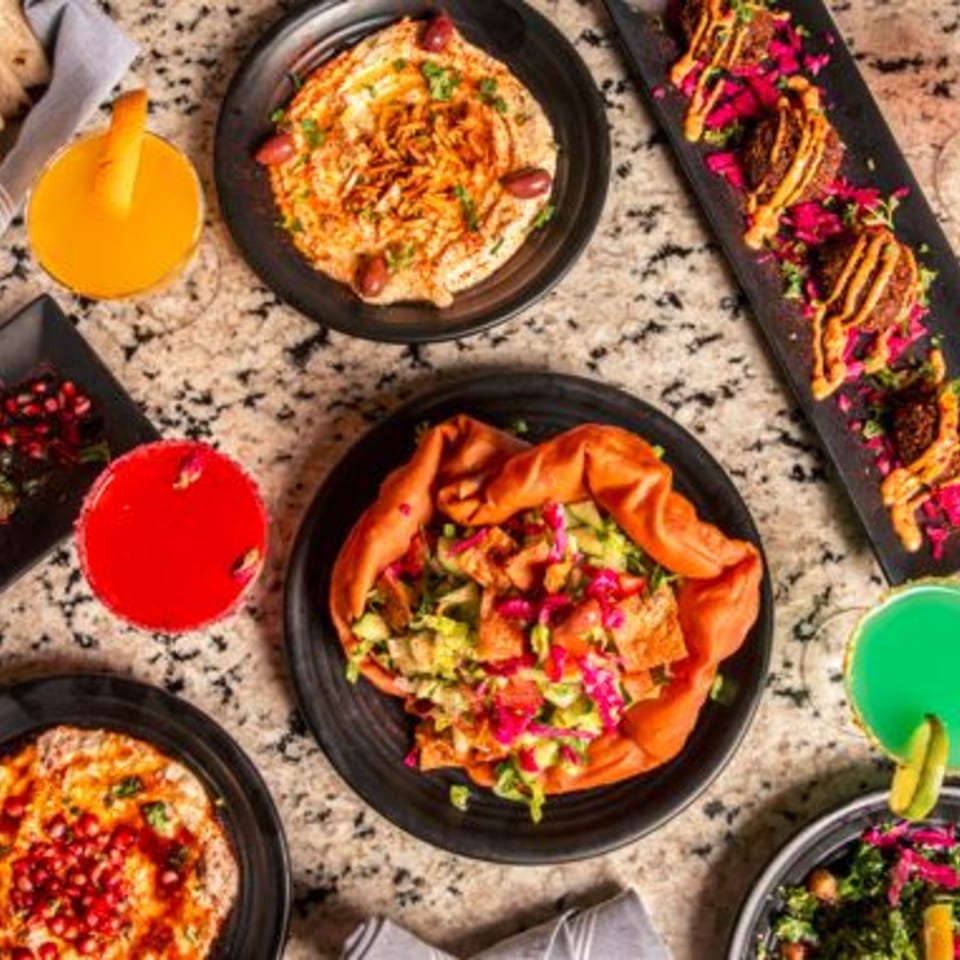 Overhead view of a spread of Middle Eastern dishes, including hummus, falafel, and salads.